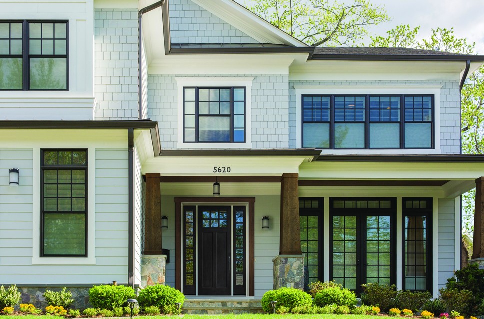 Picture of the front exterior of a modern white renovated house with black window grids.